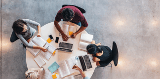 Students sat around a table studying with laptops and notes