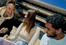 A group of three La Trobe students smiling and having conversation at a table