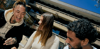 A group of three La Trobe students smiling and having conversation at a table