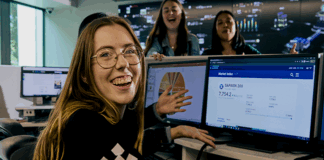 La Trobe business student smiling at camera with computer in background