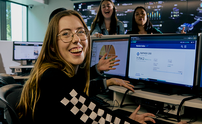 La Trobe business student smiling at camera with computer in background