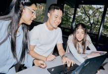 Three La Trobe students gathered around a laptop