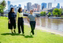 Three students walking along the Yarra River
