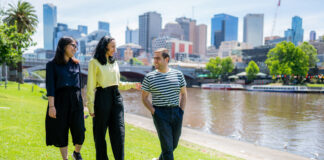 Three students walking along the Yarra River