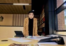 A student standing at a desk with papers on it
