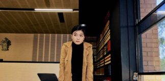 A student standing at a desk with papers on it