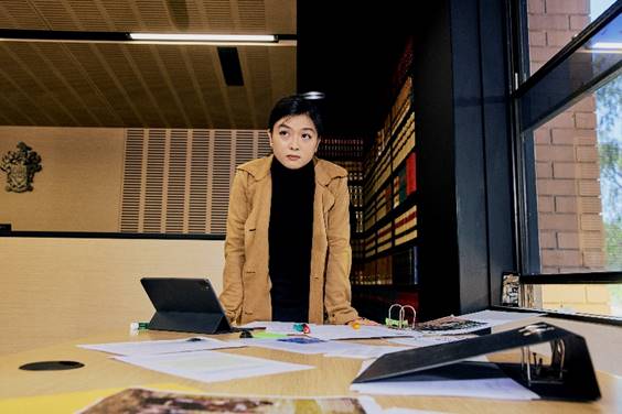 A student standing at a desk with papers on it