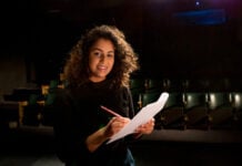 2024 Multicultural Youth Awards finalist Lakshmi Ganapathy on a theatre stage with a piece of paper