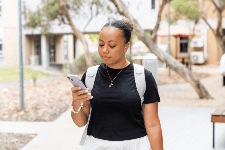 A student walking looking at their phone