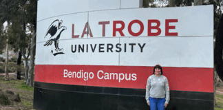 Student Justine standing in front of La Trobe sign in Bendigo