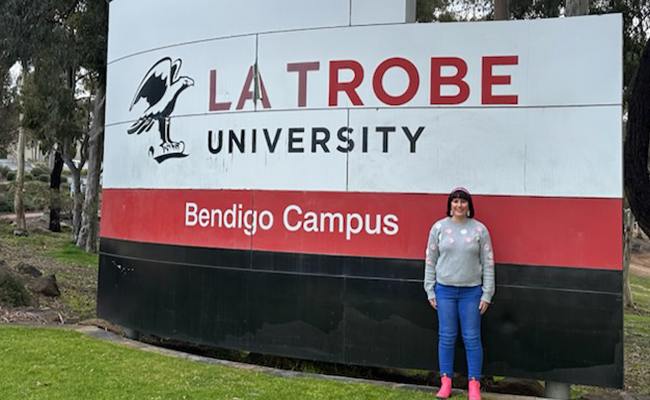 Student Justine standing in front of La Trobe sign in Bendigo
