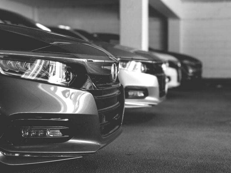 Grey and white image of cars parked in a row