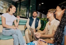 A group of students sitting together on a bench inside and talking