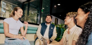 A group of students sitting together on a bench inside and talking
