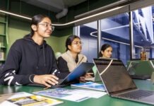 Three students sitting with their laptops at a table.