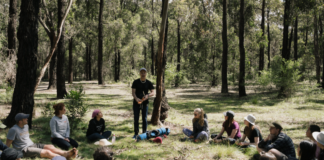 Students sitting in amongst bushland