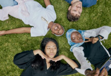 Students laying on the lawn and taking a selfie