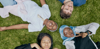 Students laying on the lawn and taking a selfie