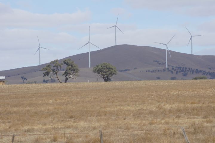 Wind turbines on a hillside from across a dry Australian field.