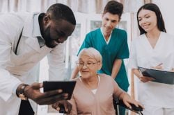 Elderly woman sitting down surrounded by doctors.