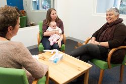 Three females sitting in room, one participant holding a baby