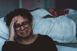 Female sitting next to bed crying