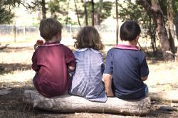 Three school children sitting outside