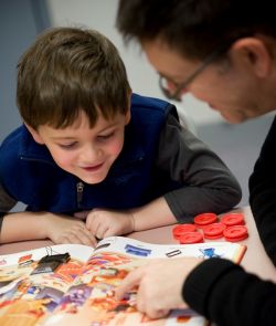 small child smiling at book with adult looking at pictures