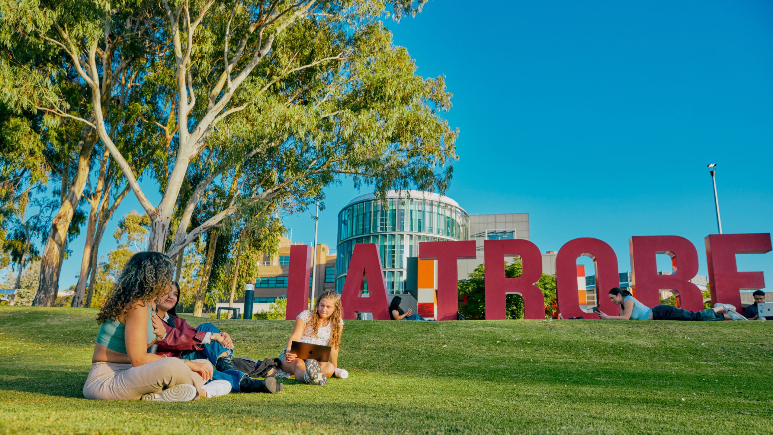 Students sitting in front of the La Trobe sign
