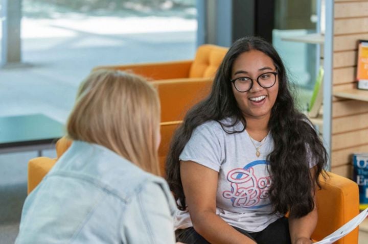Female student sitting on couches.